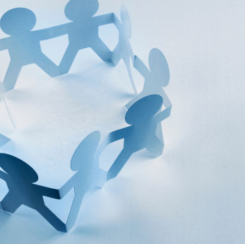 A circle of blue paper cut-out figures holding hands, symbolising community, teamwork, and inclusion