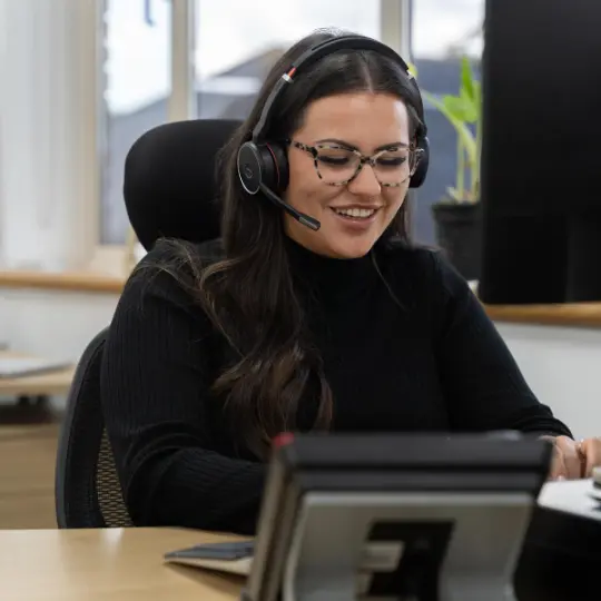 Women with headset laughing sat at desk.