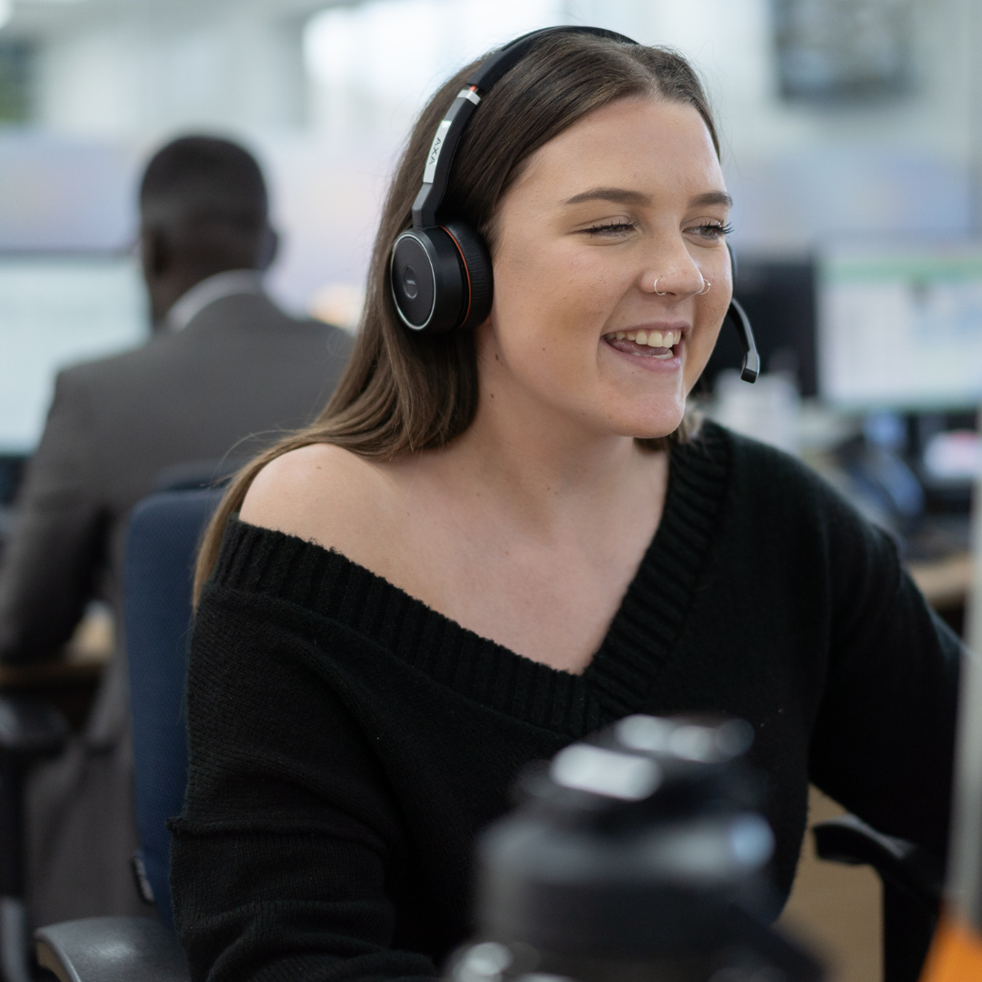 Women with headset laughing sat at desk.